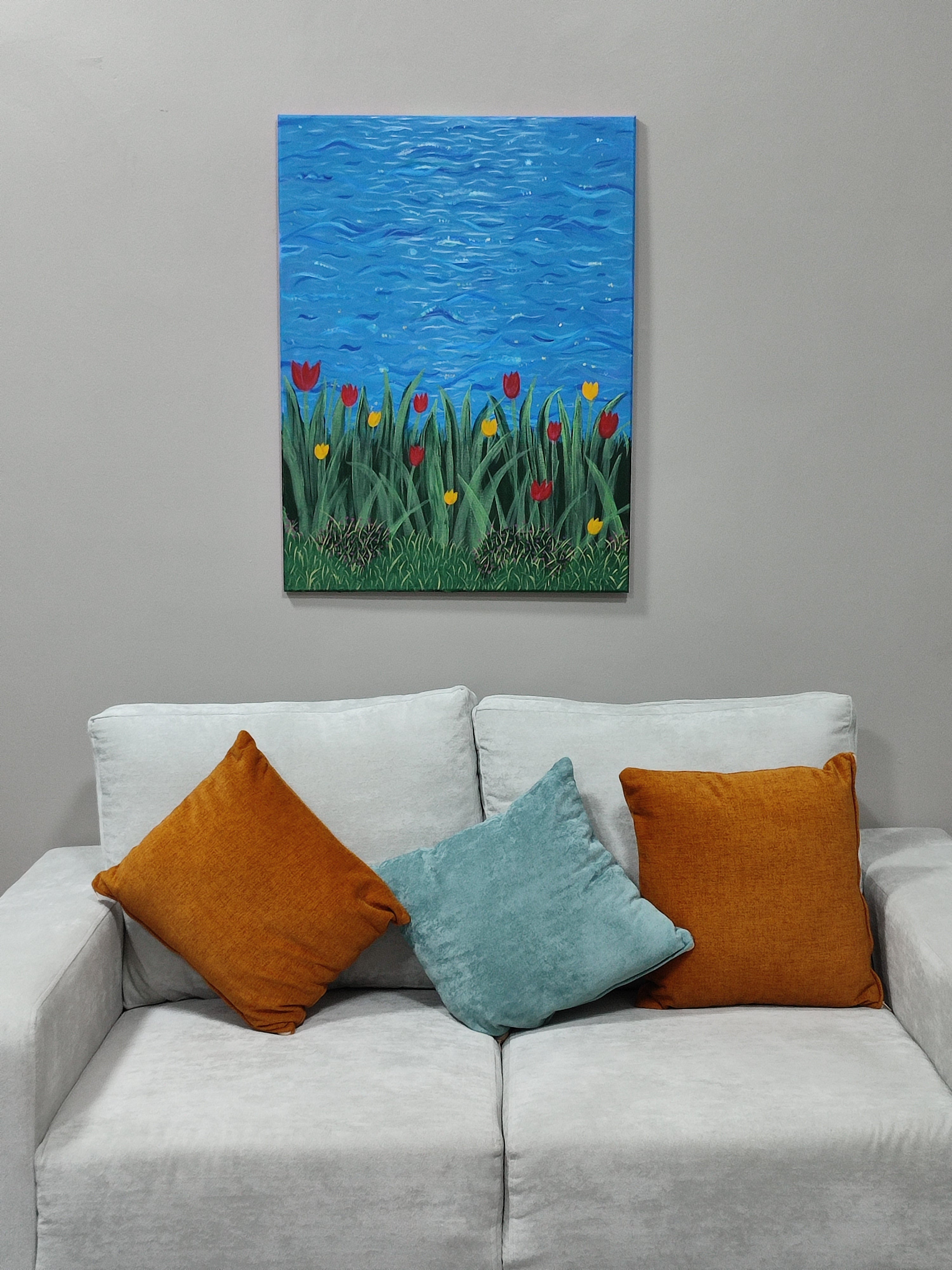 Gray sofa with colorful pillows and a painting of flowers on a gray wall.