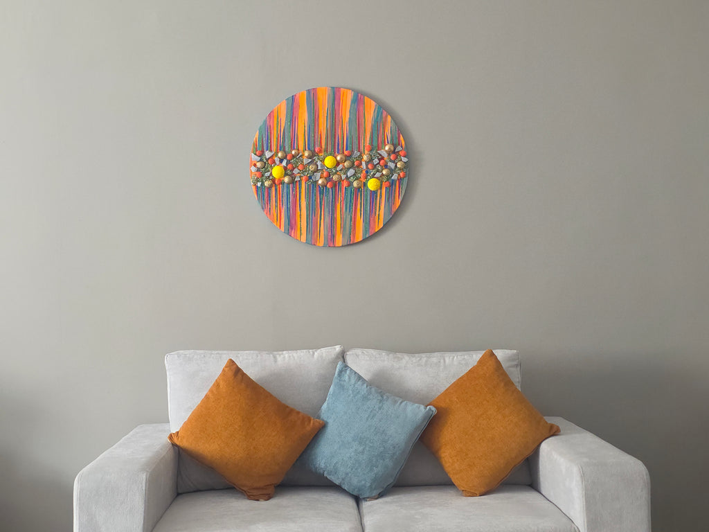 Colorful abstract wall art above a gray sofa with patterned cushions.