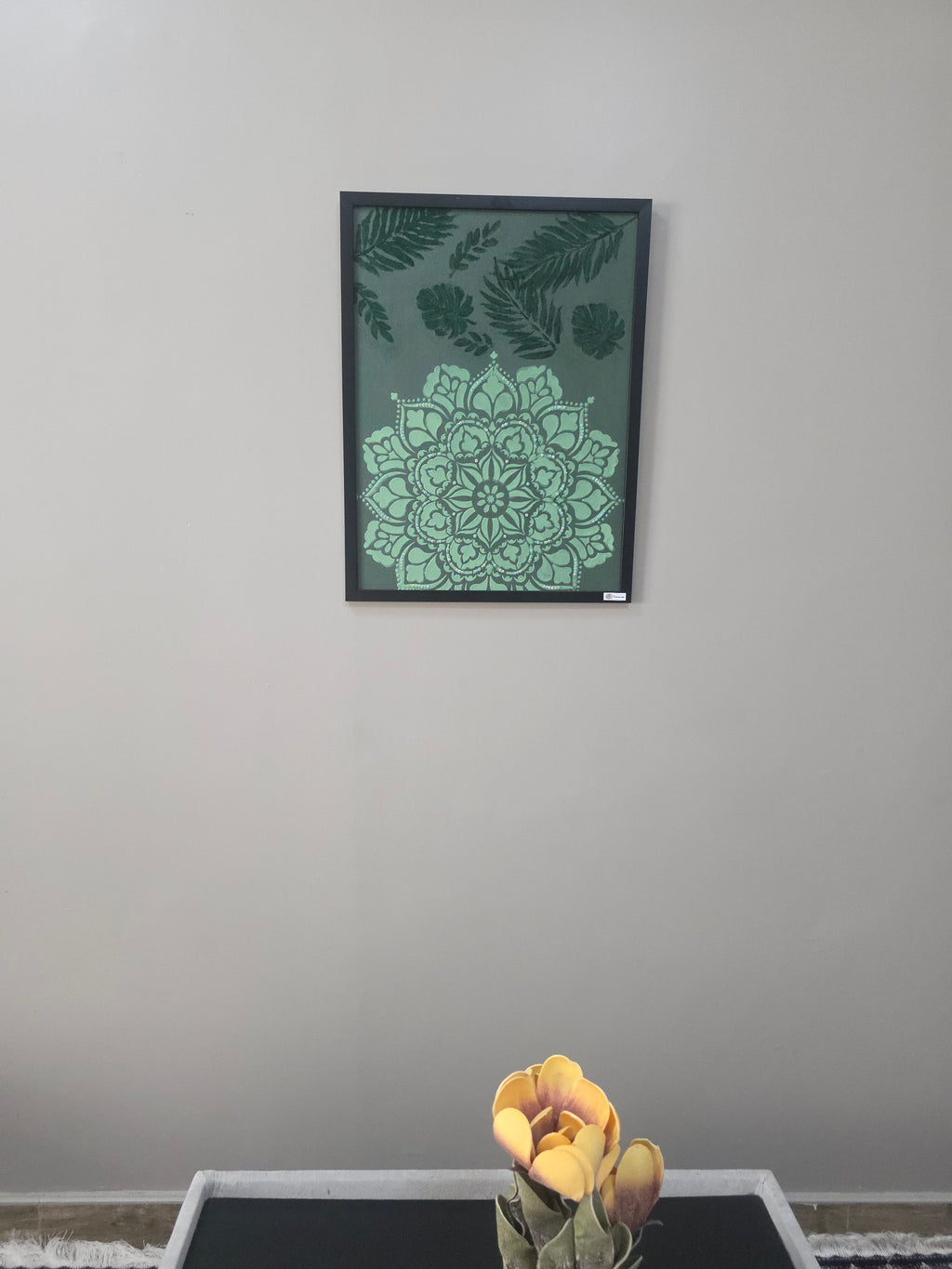 Decorative wall art with green mandala design on a plain wall.