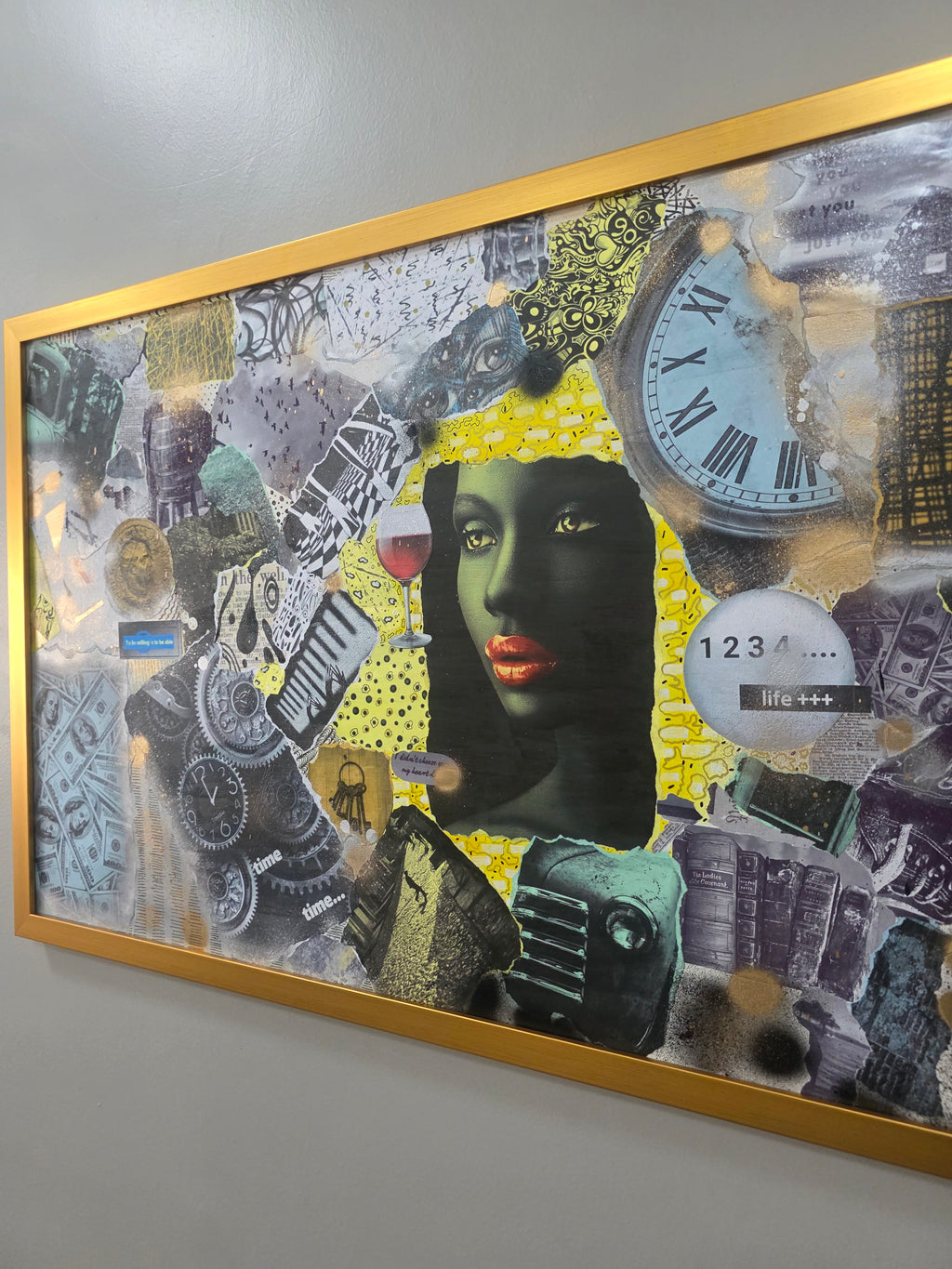 Framed collage art with a woman's face and various elements on a wall.