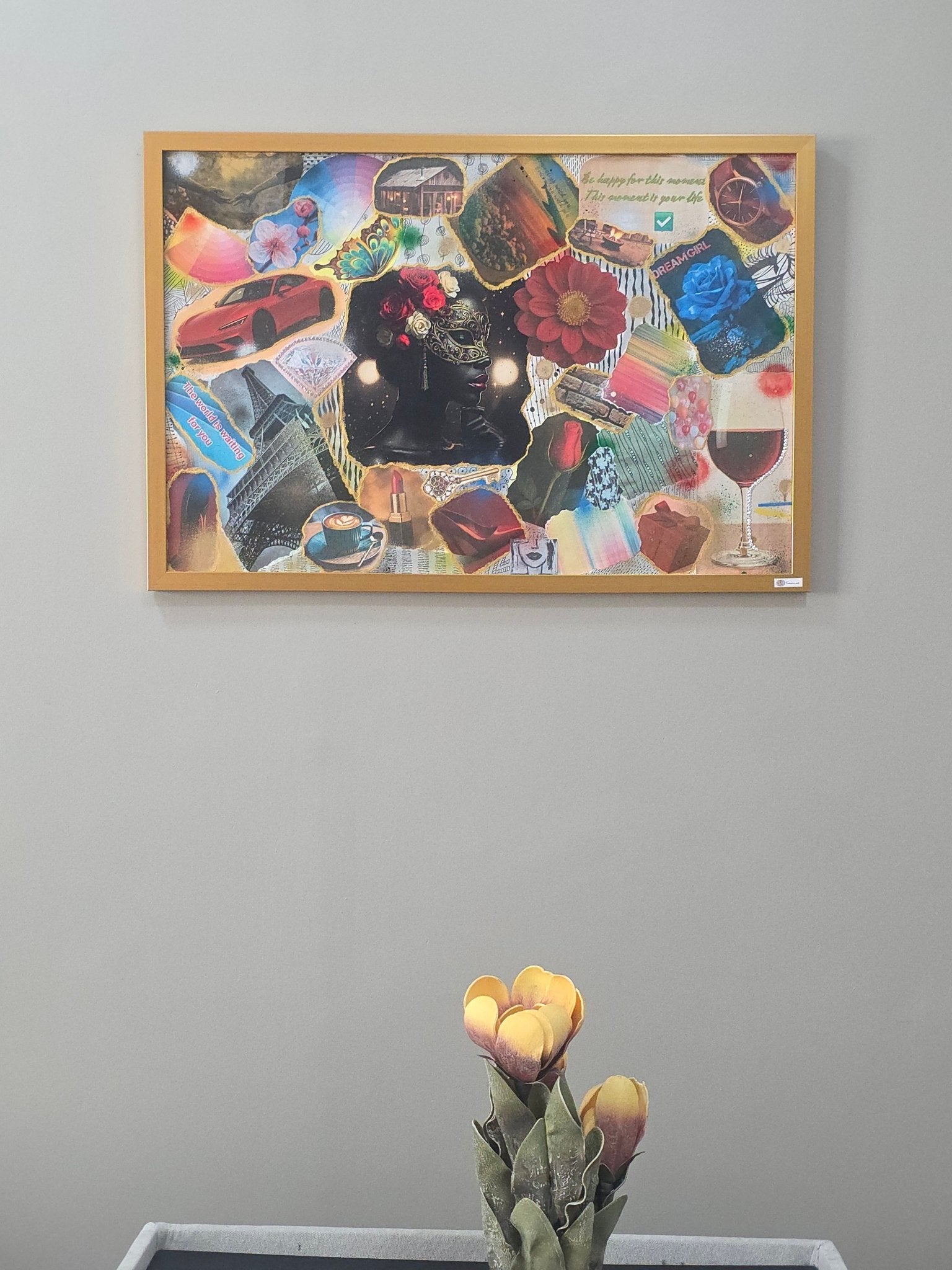 Framed collage on a wall with a vase of flowers in the foreground.