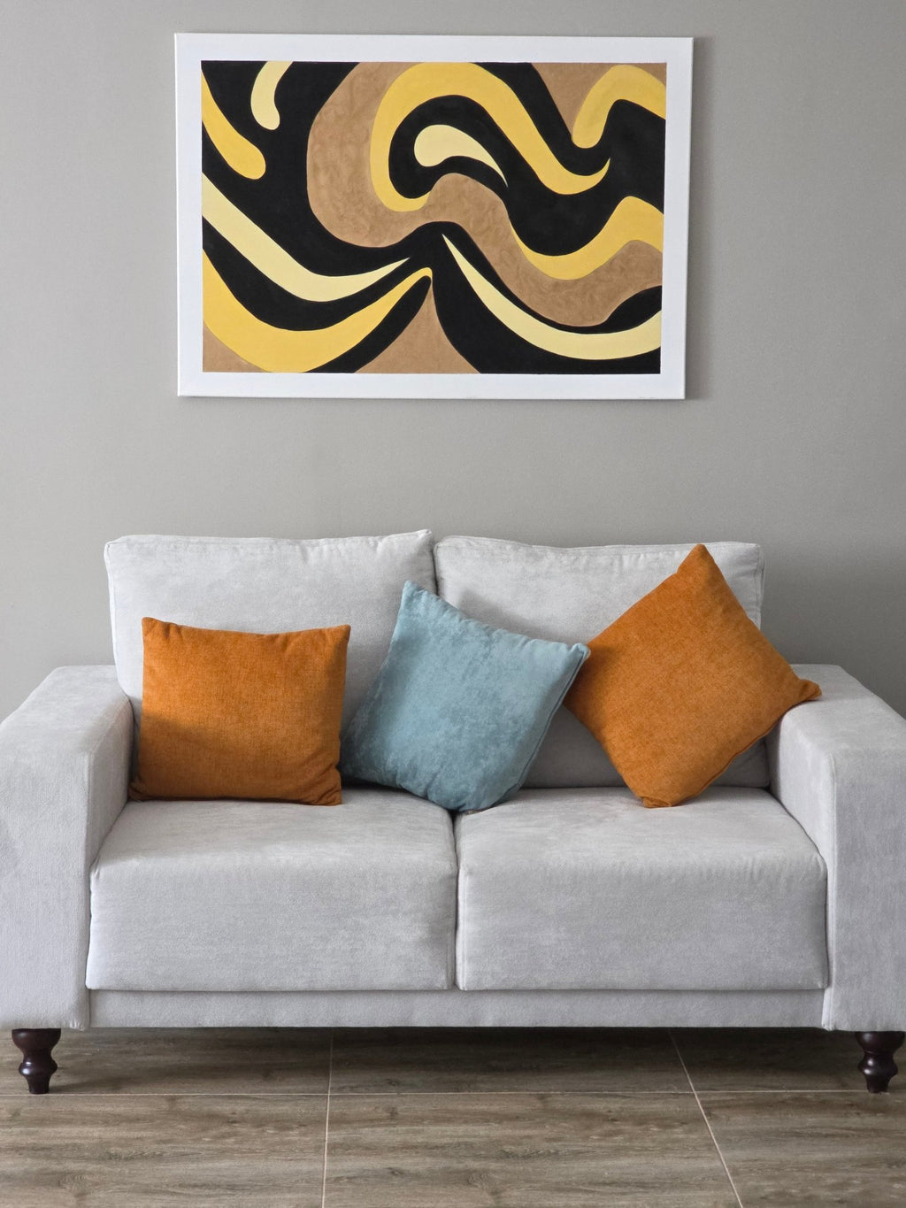 CatArts Gilded Tides minimalist abstract painting hanging above a contemporary grey sofa with orange accents