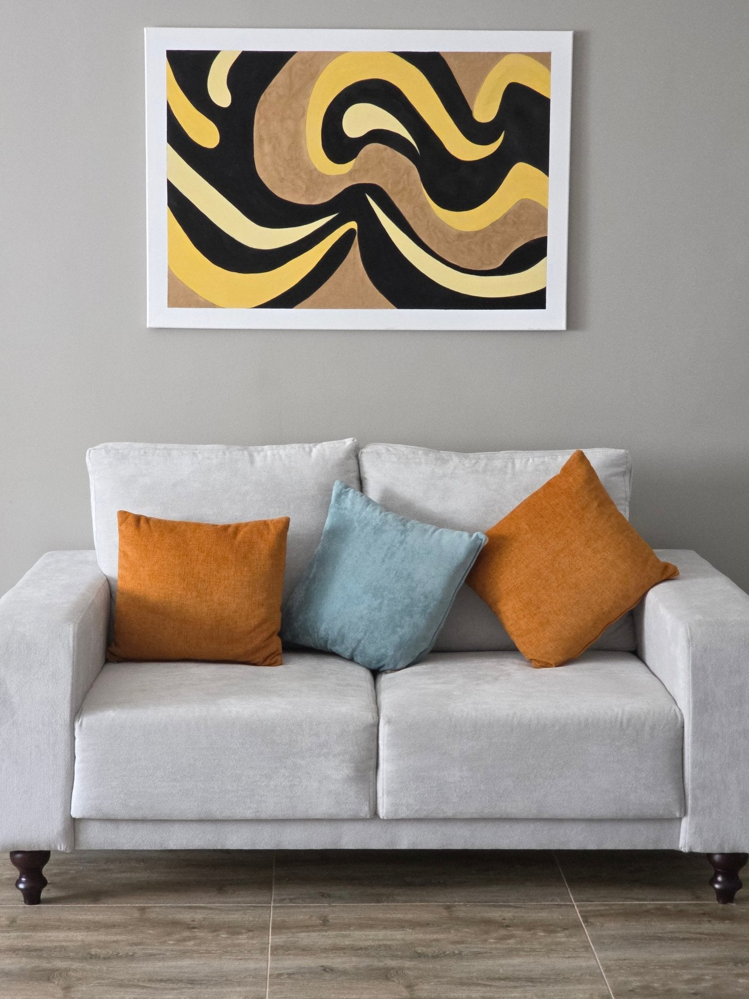CatArts Gilded Tides minimalist abstract painting hanging above a contemporary grey sofa with orange accents