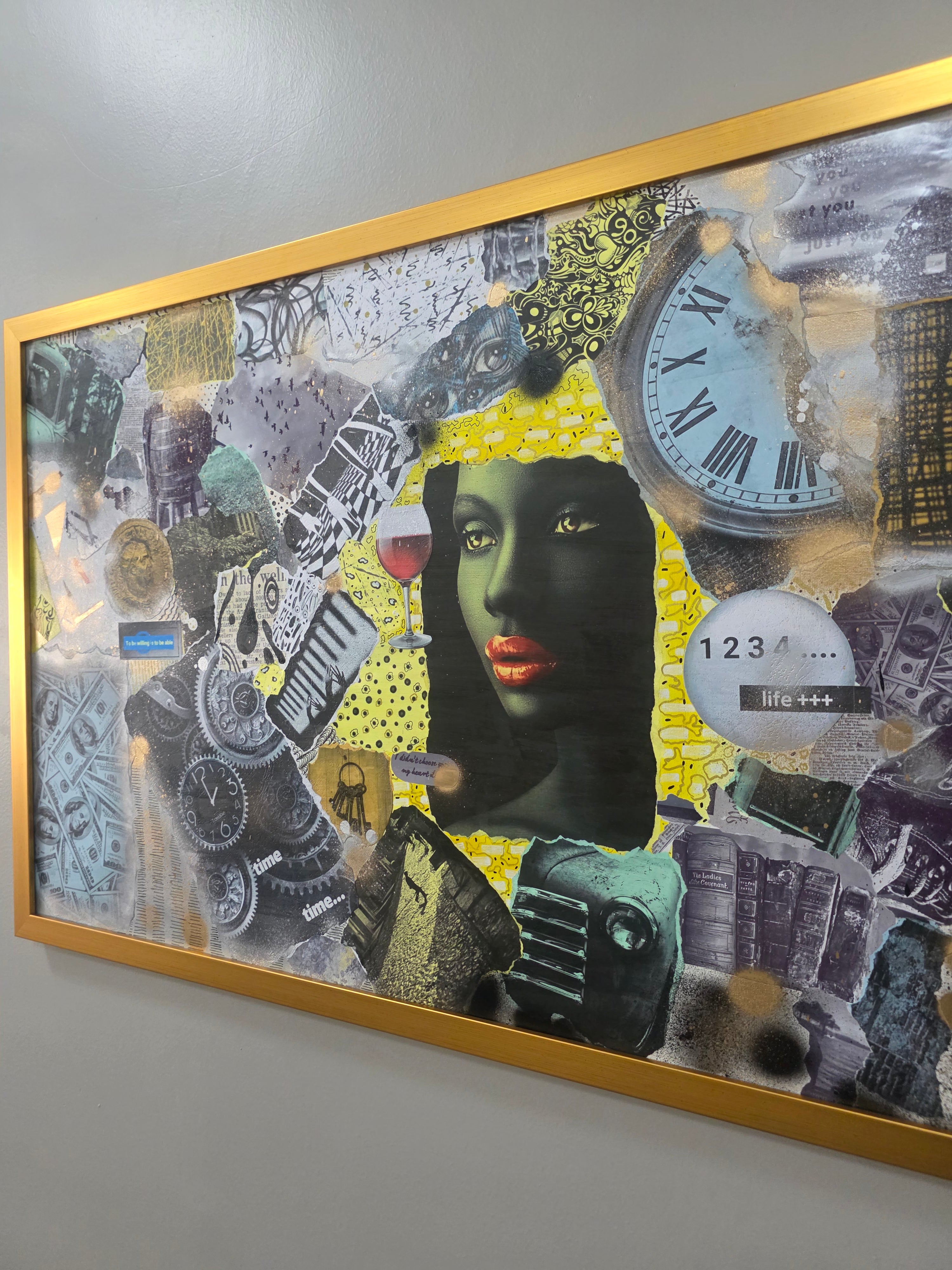 Framed collage art with a woman's face and various elements on a gray wall.